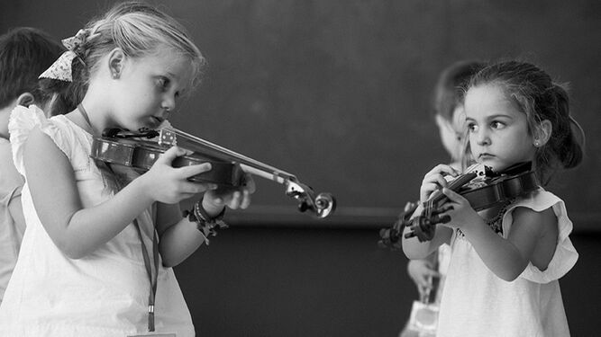 Dos niñas portan sendos violines en uno de los cursos de iniciación realizados por la Fundación Barenboim-Said en  otras provincias andaluzas.